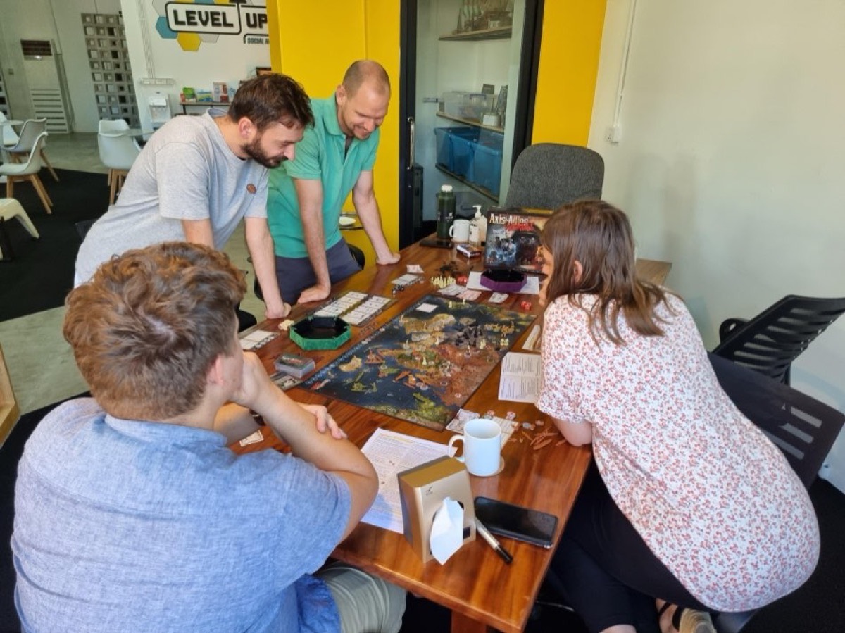 Friends around a big table mid board-game at Level Up