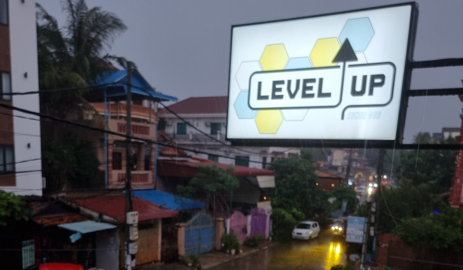 Level Up's glowing sign over a rainy Siem Reap street in the evening