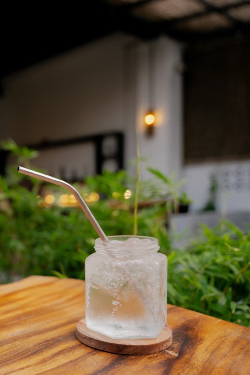 An iced drink on a wooden table amid Nomad's greenery